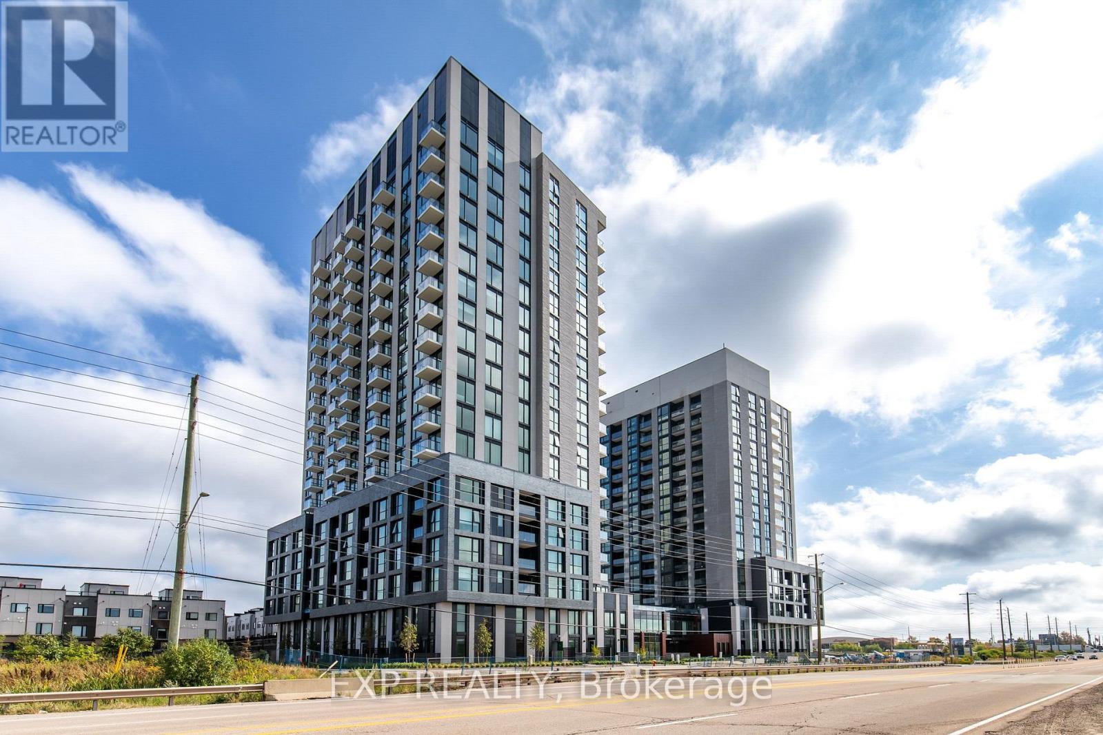 Two modern buildings with glass windows are under a blue sky with clouds.