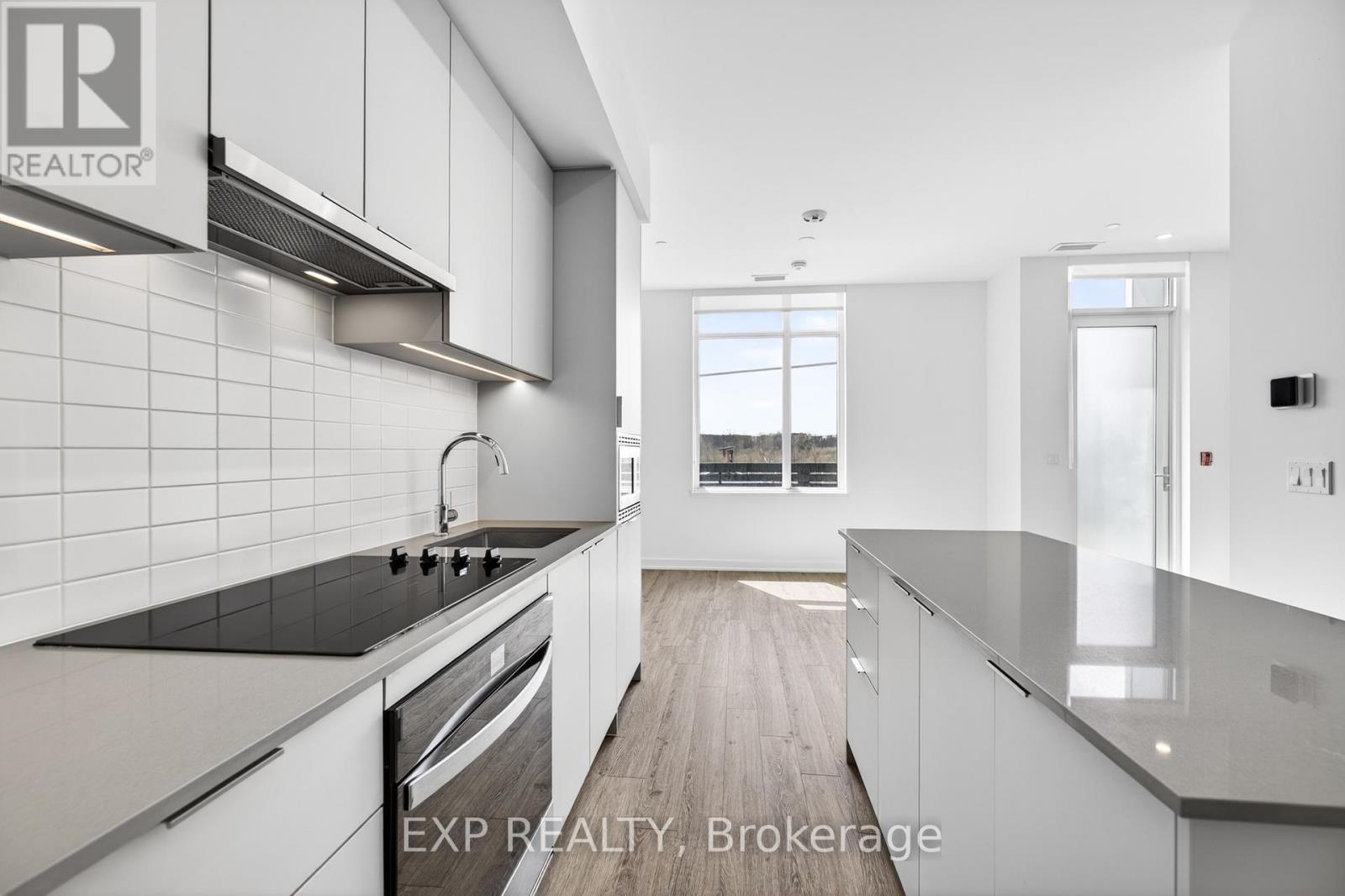 A modern kitchen with white cabinets and black countertops.