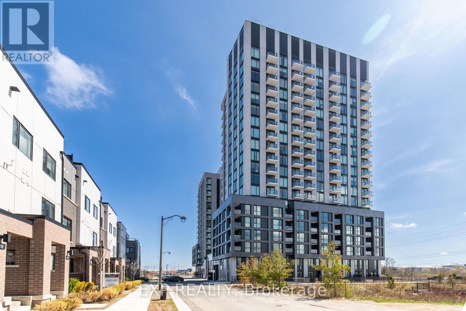A modern high-rise building is the focal point of this image, surrounded by smaller buildings and a clear sky.