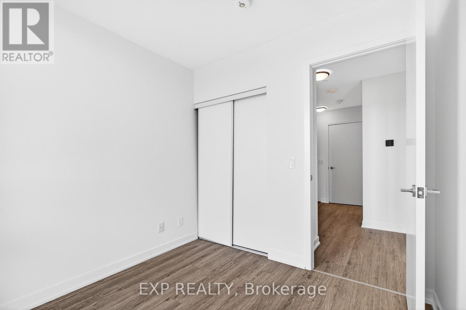 A white bedroom with a sliding door and a wooden floor.