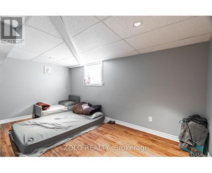A bedroom with a bed covered in a grey blanket.