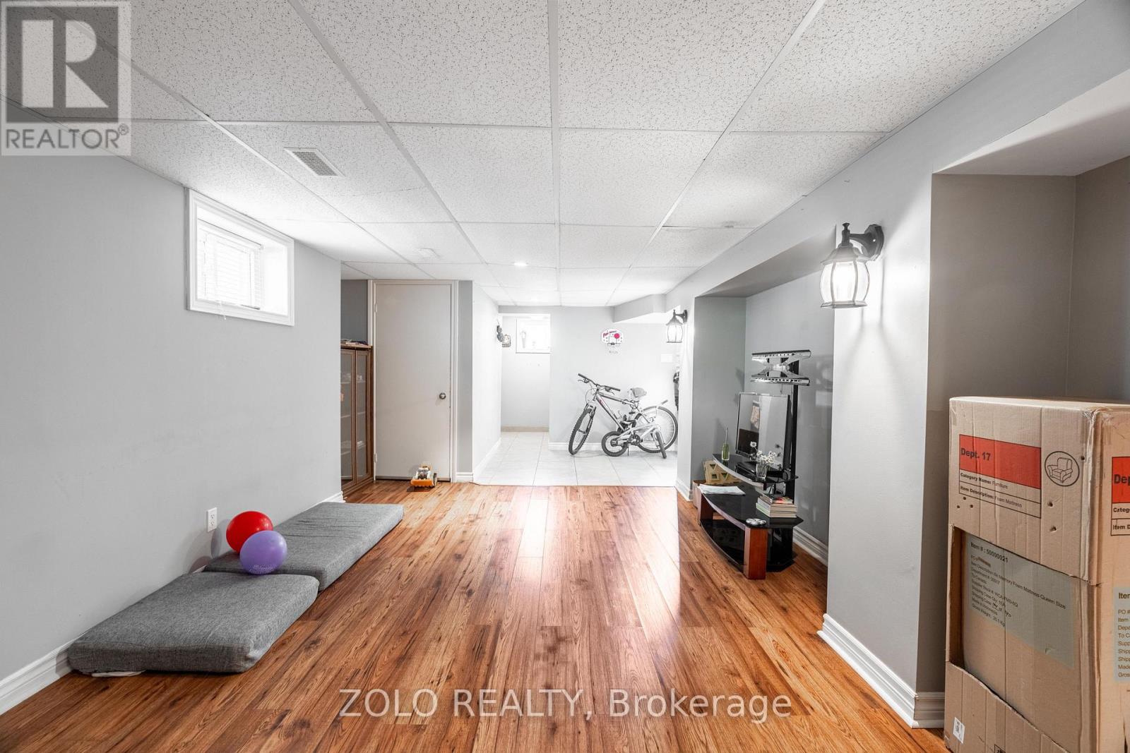 A room with a grey couch and a bicycle in the background.