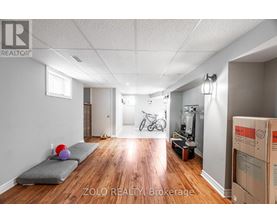 A room with a grey couch and a bicycle in the background.