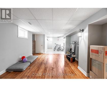 A room with a grey couch and a bicycle in the background.