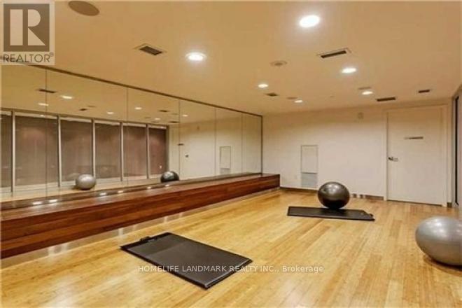 A spacious room with wooden floors and mirrors on the wall.