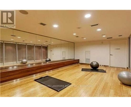 A spacious room with wooden floors and mirrors on the wall.