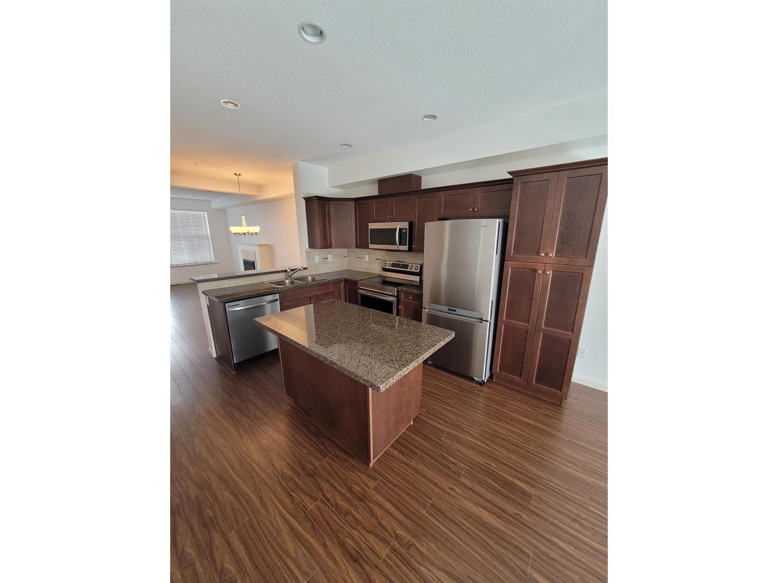 A kitchen with brown cabinets and a granite countertop.