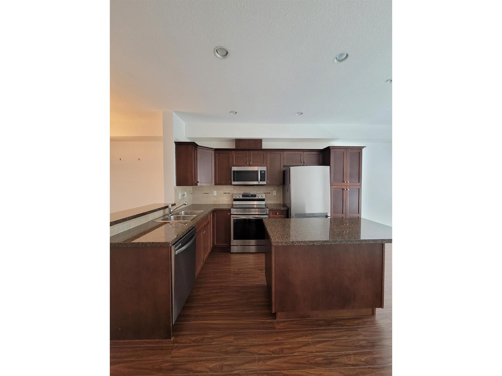 A kitchen with dark wood floors and a white ceiling.