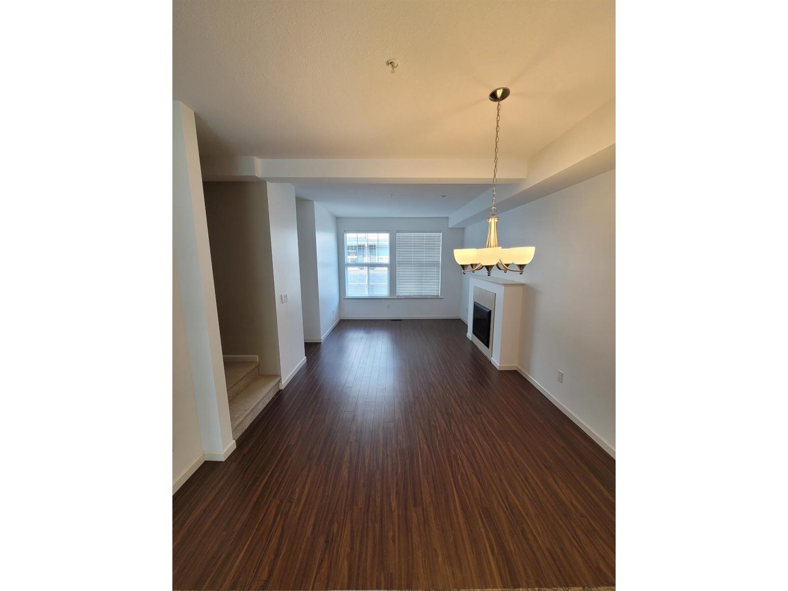 A long hallway with wood floors and a chandelier hanging from the ceiling.