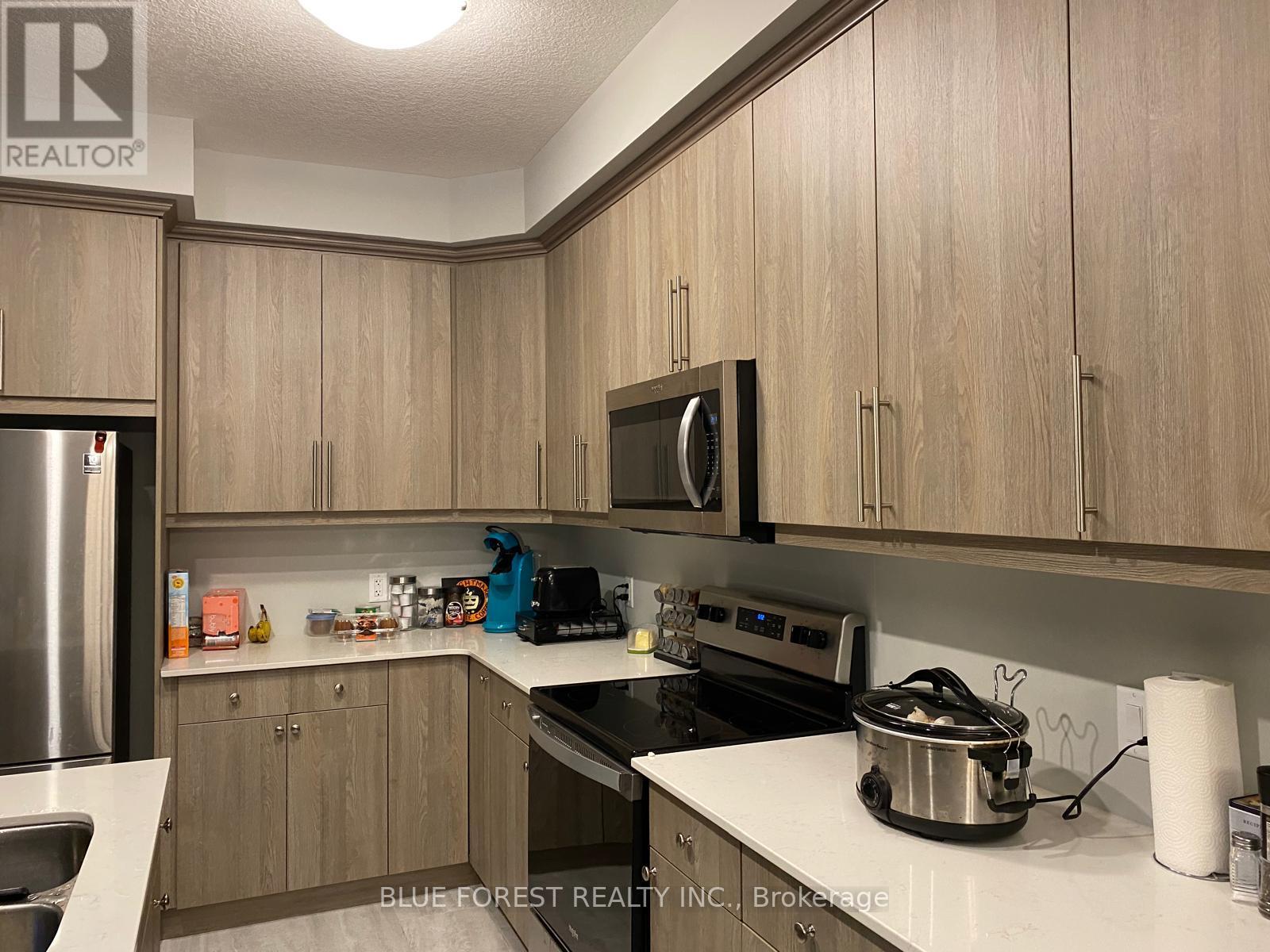 A kitchen with wooden cabinets and a stainless steel refrigerator.