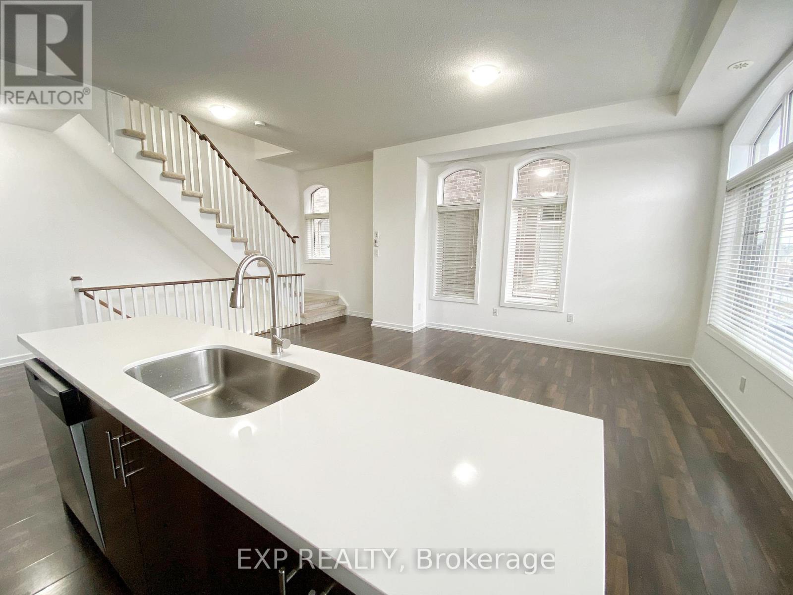A kitchen with a stainless steel sink and wooden floors.