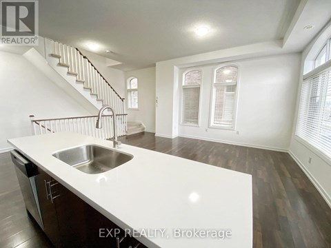 A kitchen with a stainless steel sink and wooden floors.