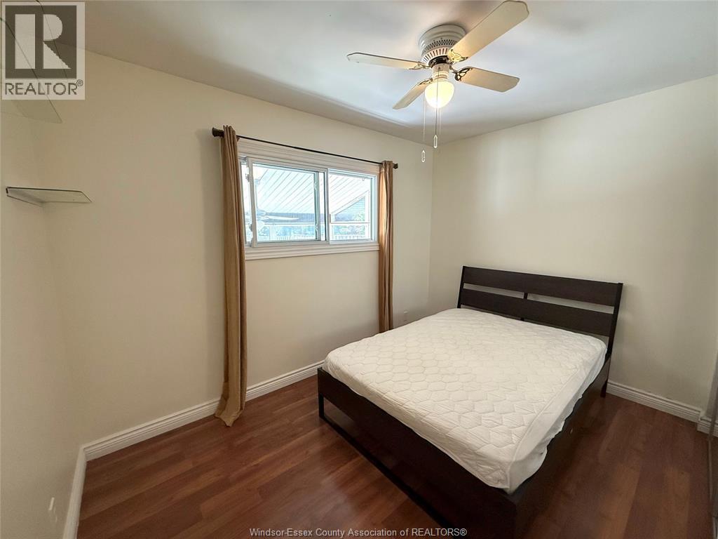 A bedroom with a bed, a ceiling fan, and a window with curtains.