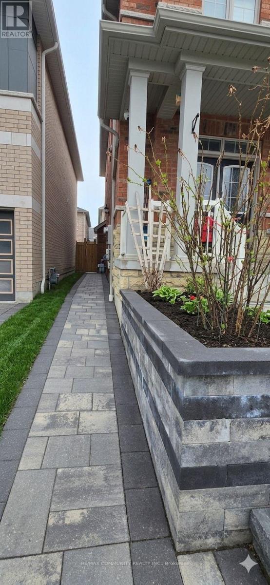 A concrete walkway leads to a house with a white porch.