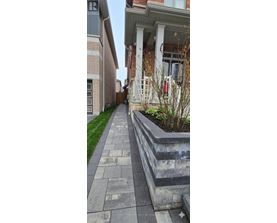 A concrete walkway leads to a house with a white porch.