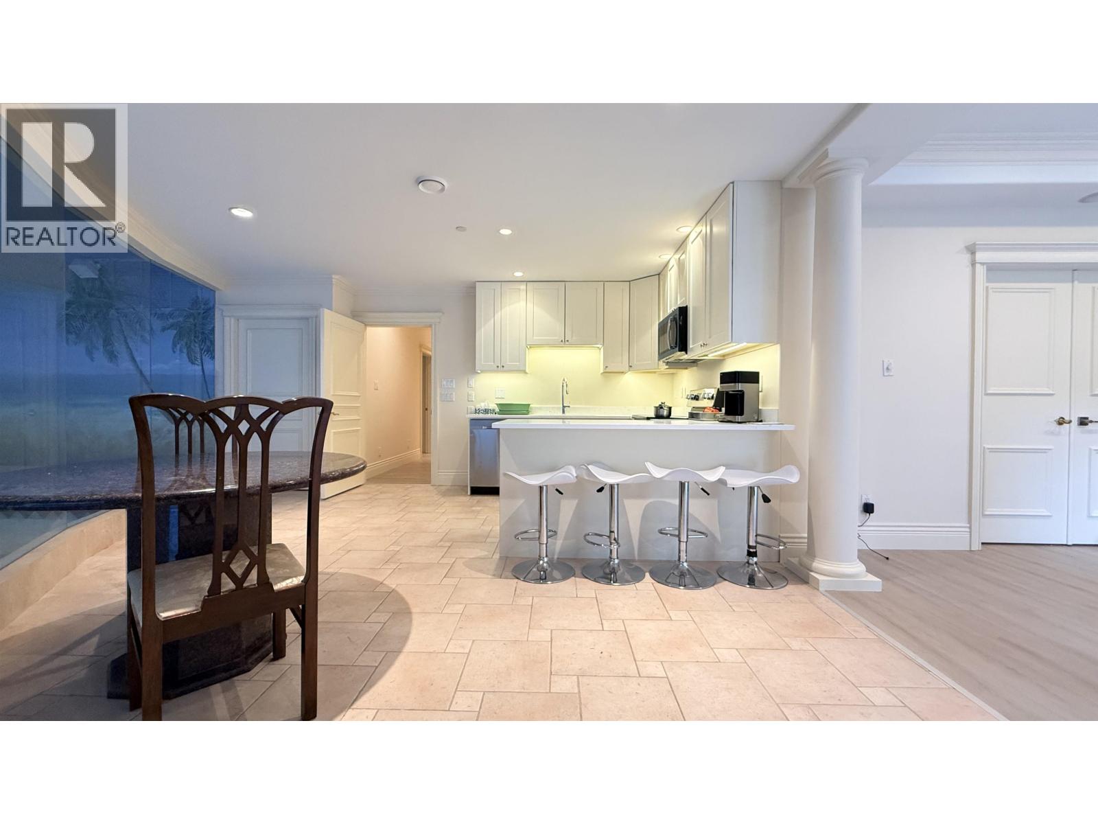 A well-lit kitchen with a bar stool and a dining table.