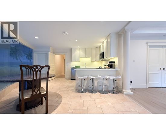 A well-lit kitchen with a bar stool and a dining table.