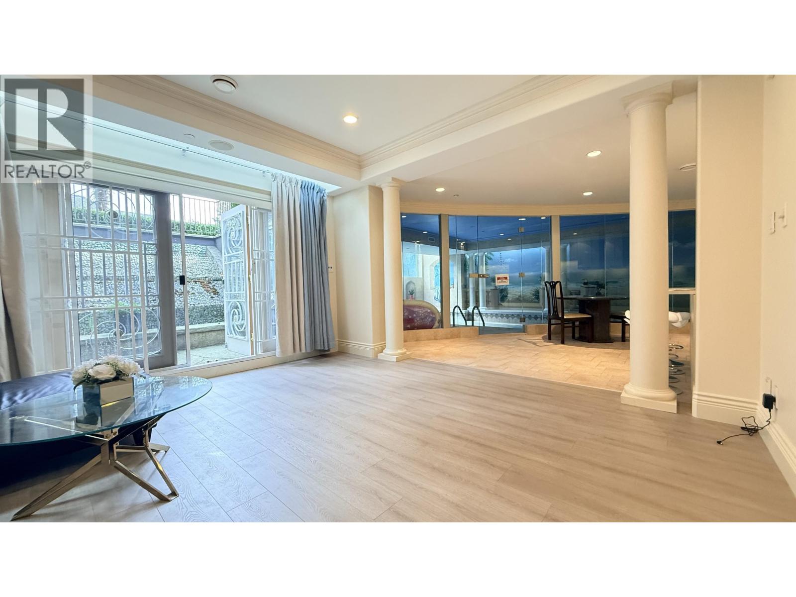 A spacious living room with a glass table and a view of the outside.