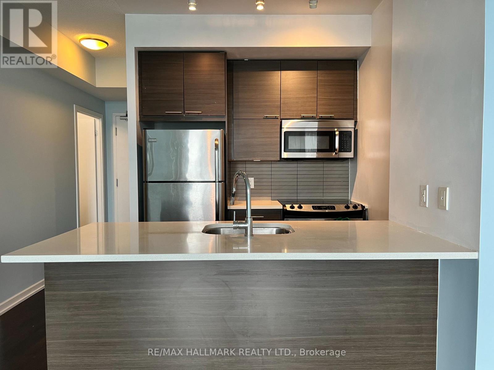 A modern kitchen with a stainless steel refrigerator and a microwave above the stove.
