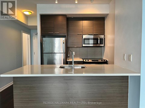A modern kitchen with a stainless steel refrigerator and a microwave above the stove.