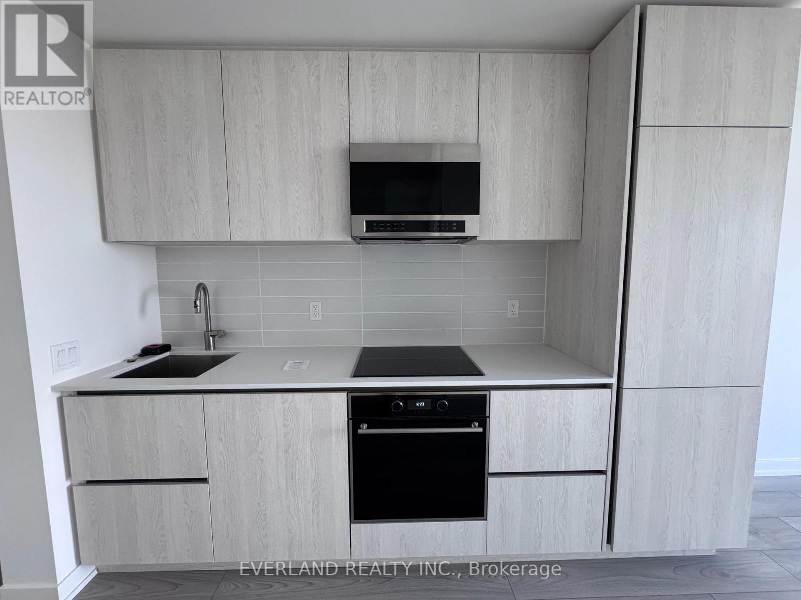 A kitchen with a sink, stove, and microwave.