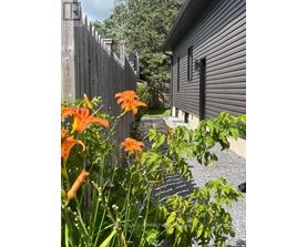 A house with a fence and flowers in front.