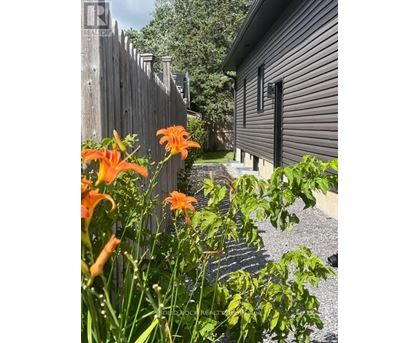 A house with a fence and flowers in front.