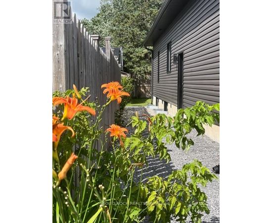 A house with a fence and flowers in front.