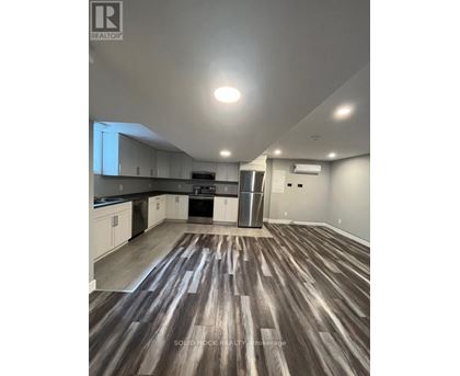 A kitchen with white cabinets and a wooden floor.