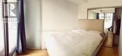A bedroom with a bed, a mirror, and a wardrobe.