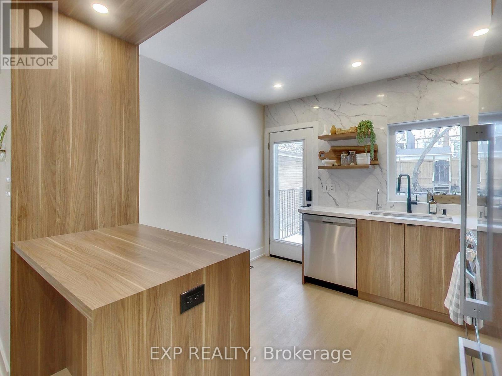 A kitchen with wooden cabinets and a marble backsplash.