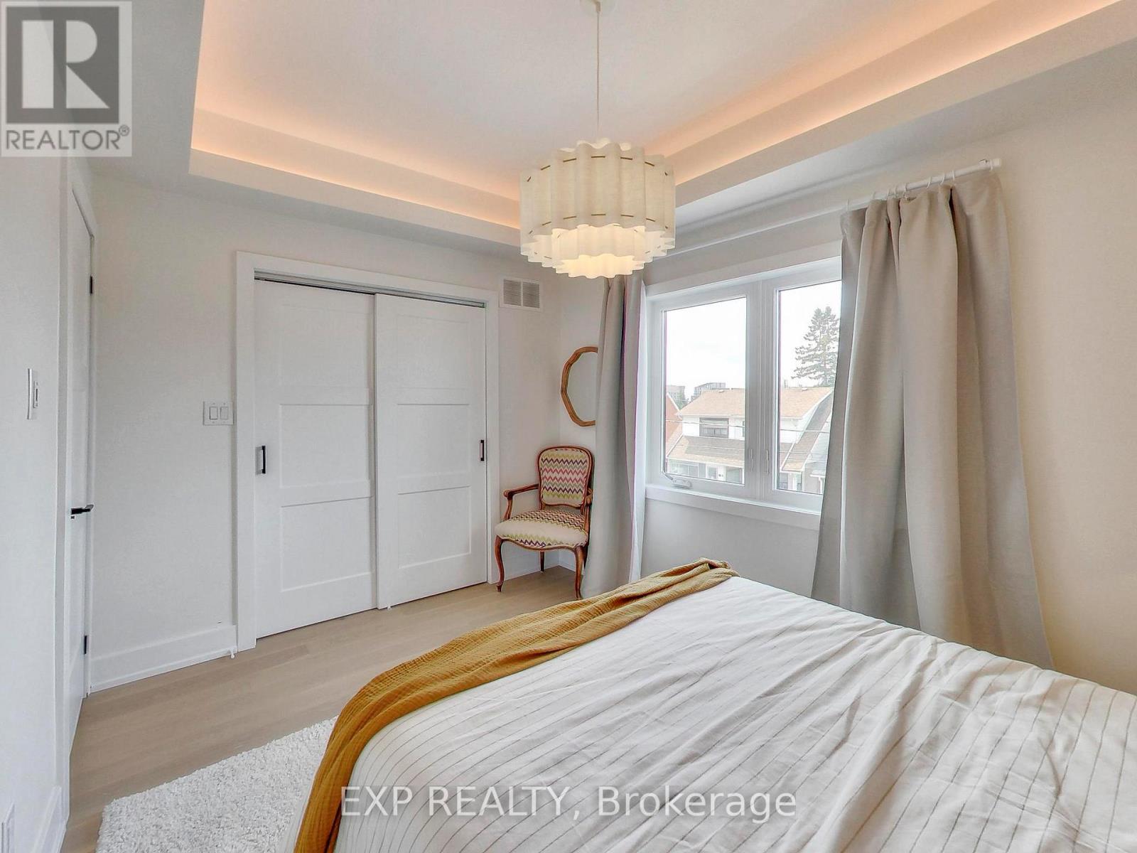 A bedroom with a large bed and a chair by the window.