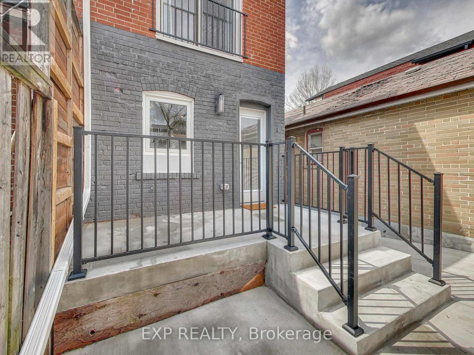 A brick building with a black railing and steps leading to a door.