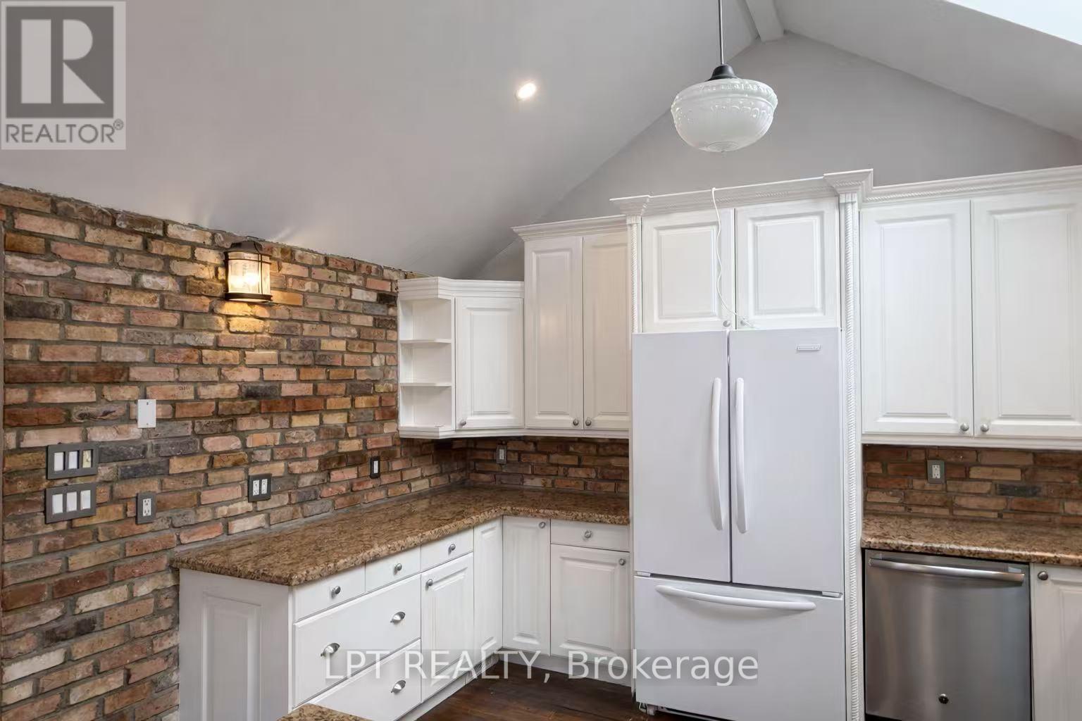 A kitchen with white cabinets and a brick wall.