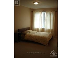 A bedroom with a bed, nightstand, and window with curtains.
