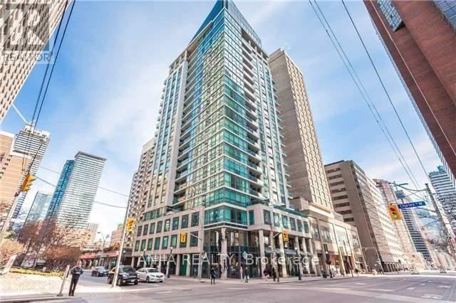 A modern glass building stands in the middle of a city street.
