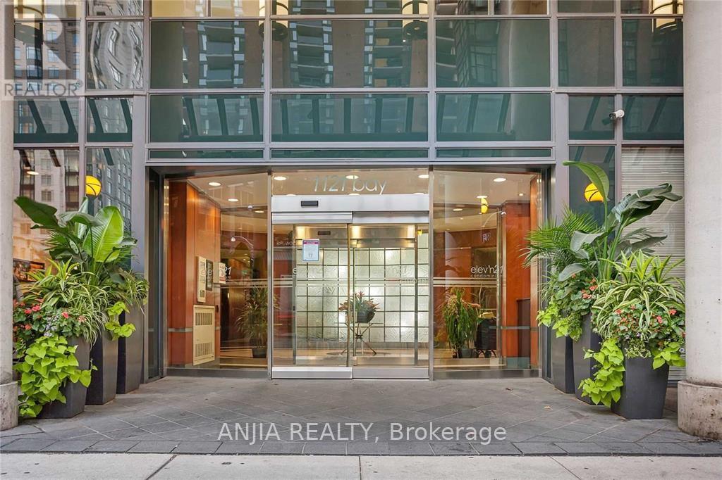The entrance to Anjia Realty Brokerage is shown with a glass door and potted plants on either side.