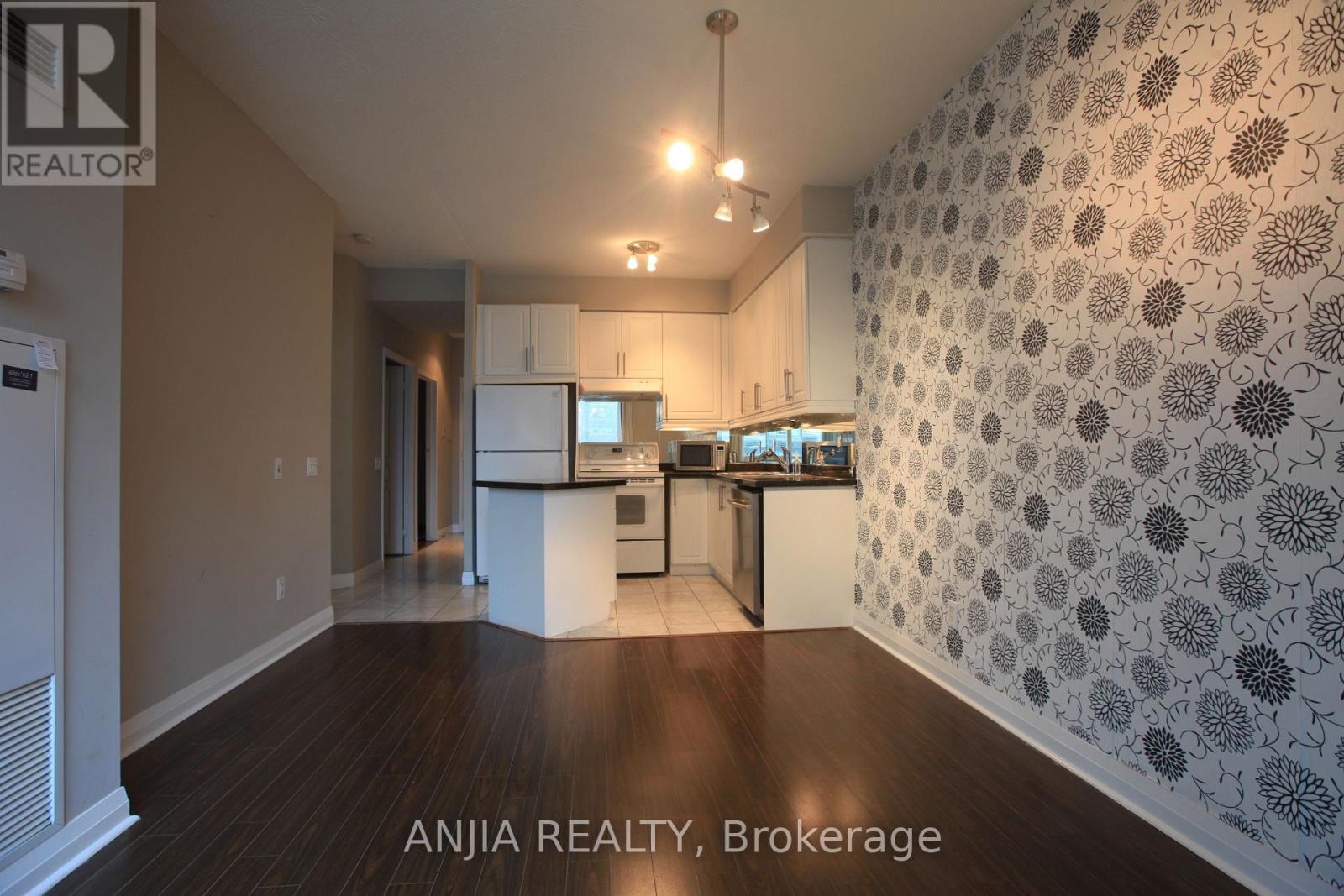 A well-lit kitchen area with a patterned wallpaper and wooden flooring.