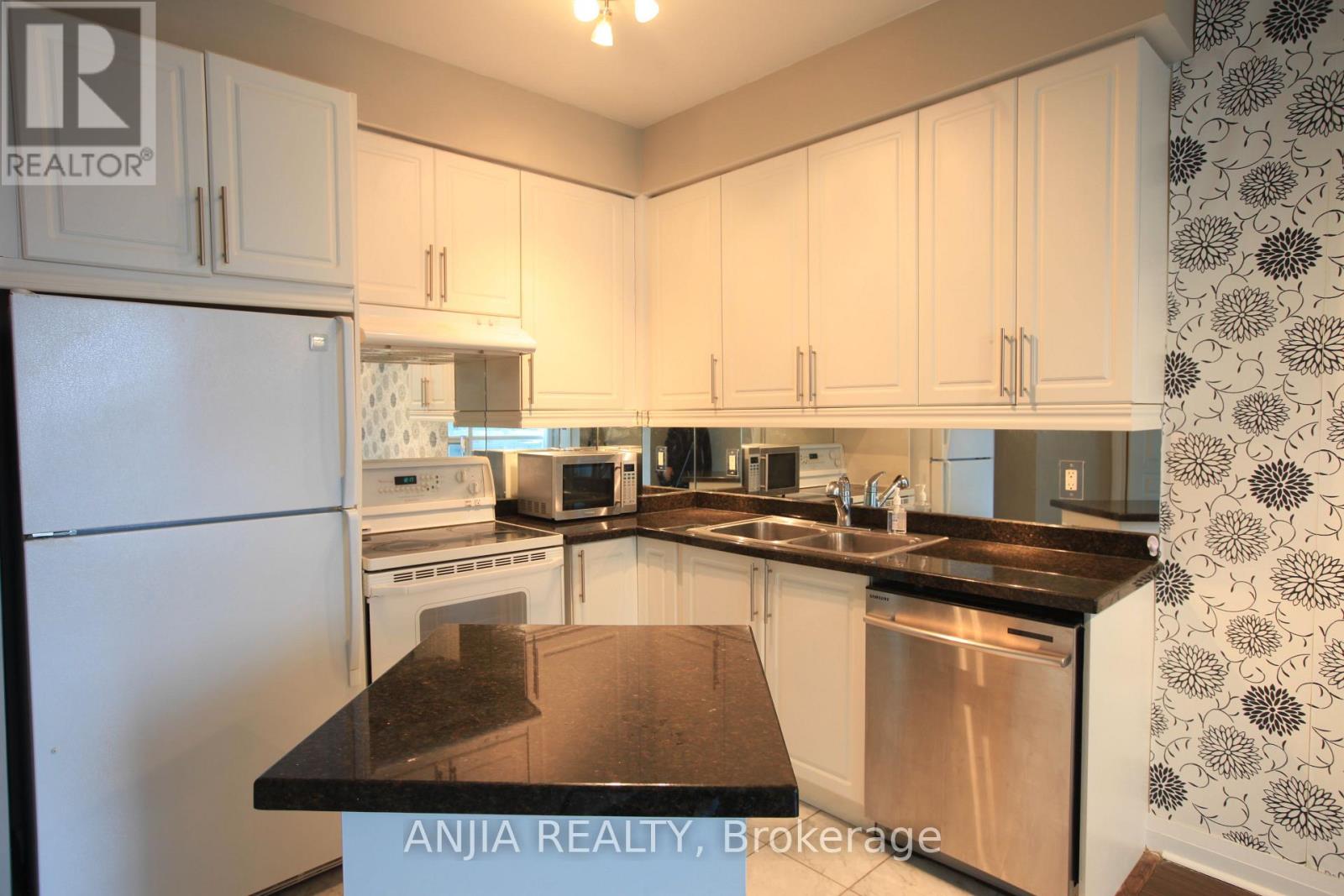 A kitchen with white cabinets and a black counter top.