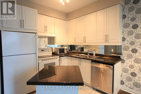 A kitchen with white cabinets and a black counter top.