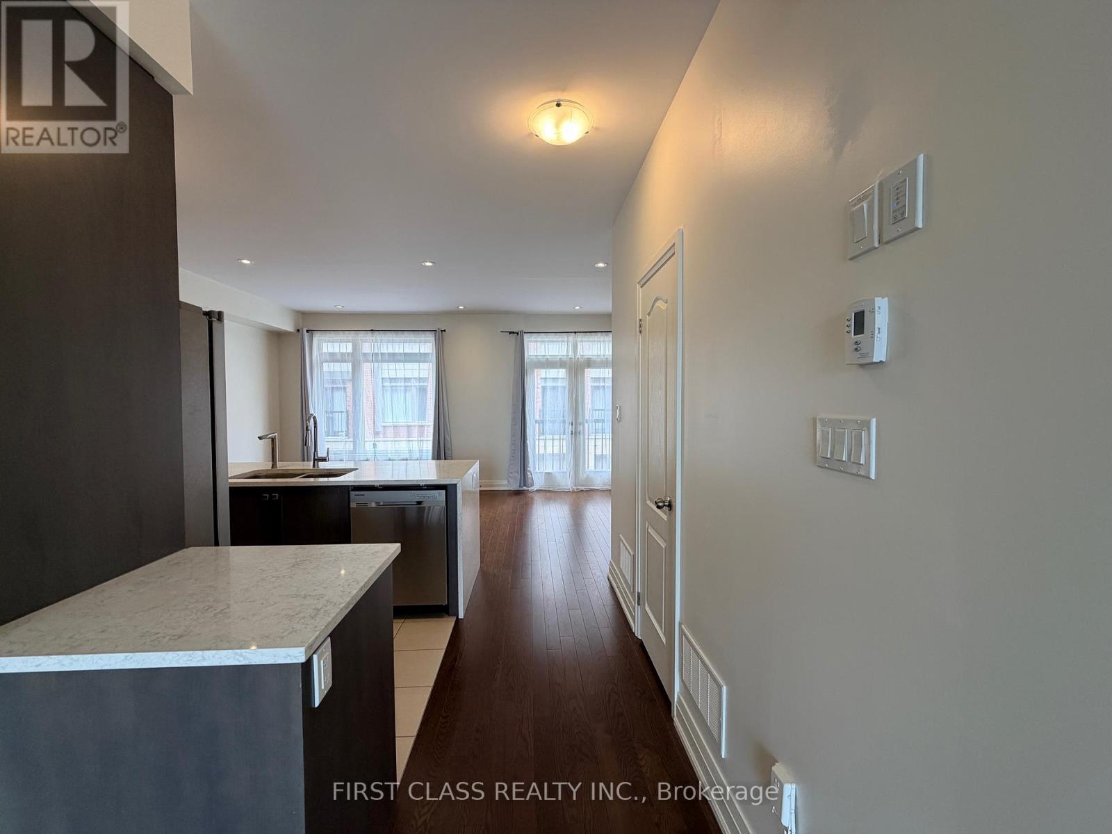 A long hallway with a marble counter top and a door at the end.