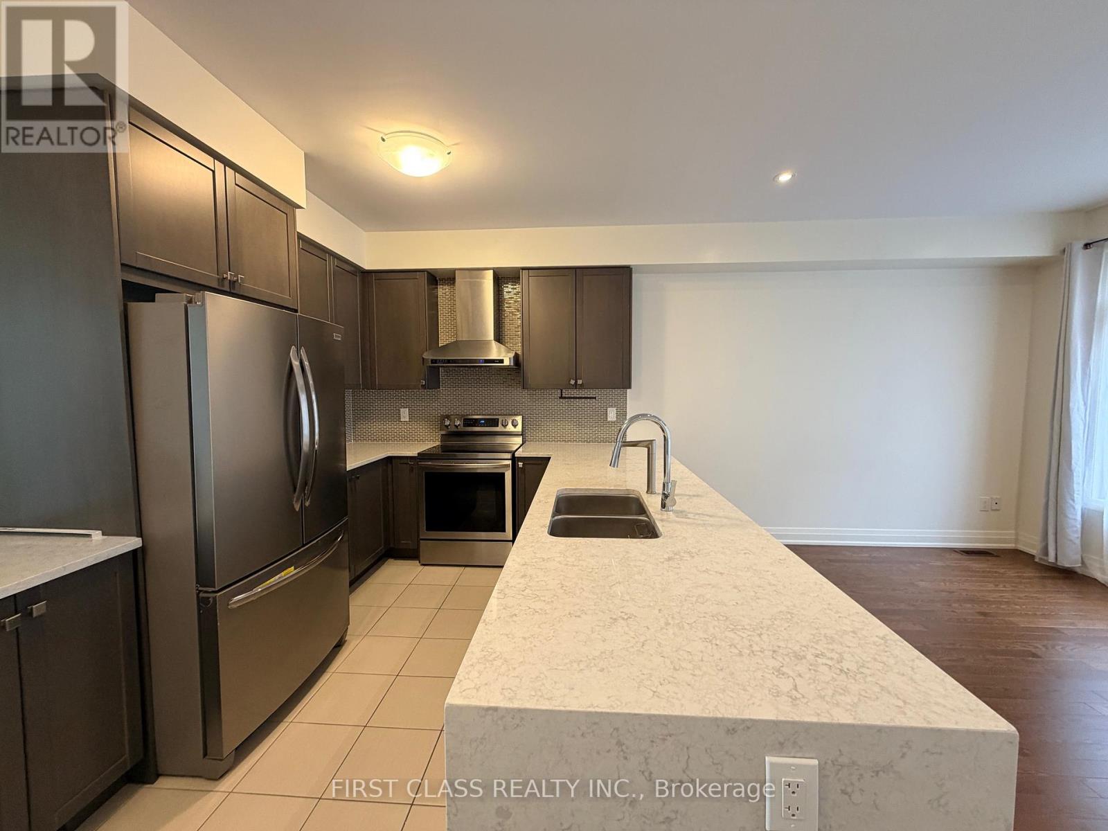 A kitchen with a refrigerator, oven, and sink.