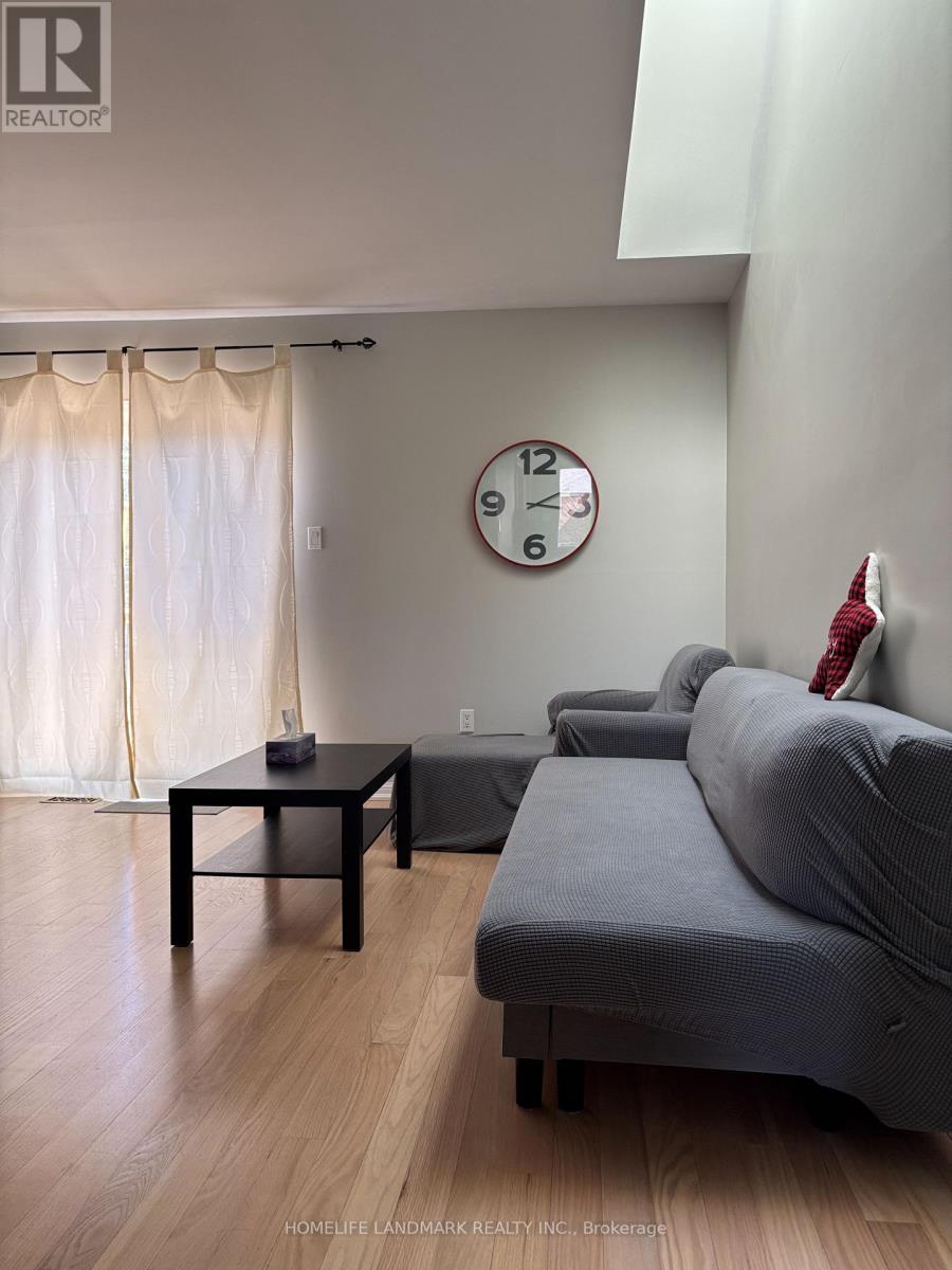 A living room with a grey couch, a black coffee table, and a clock on the wall.