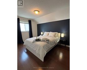 A bedroom with a bed, nightstand, and window.