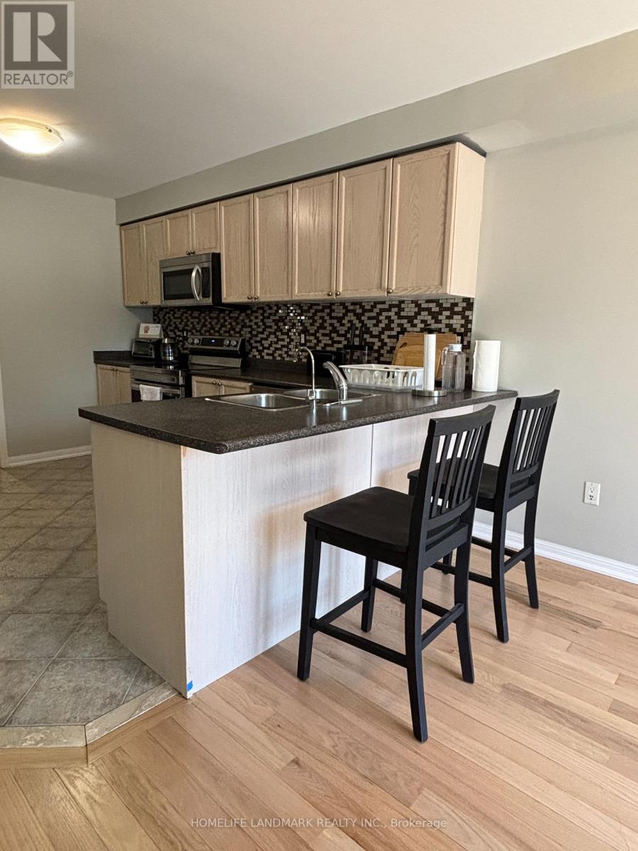 A kitchen with a black counter top and two black chairs.