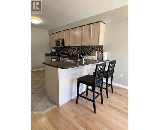 A kitchen with a black counter top and two black chairs.