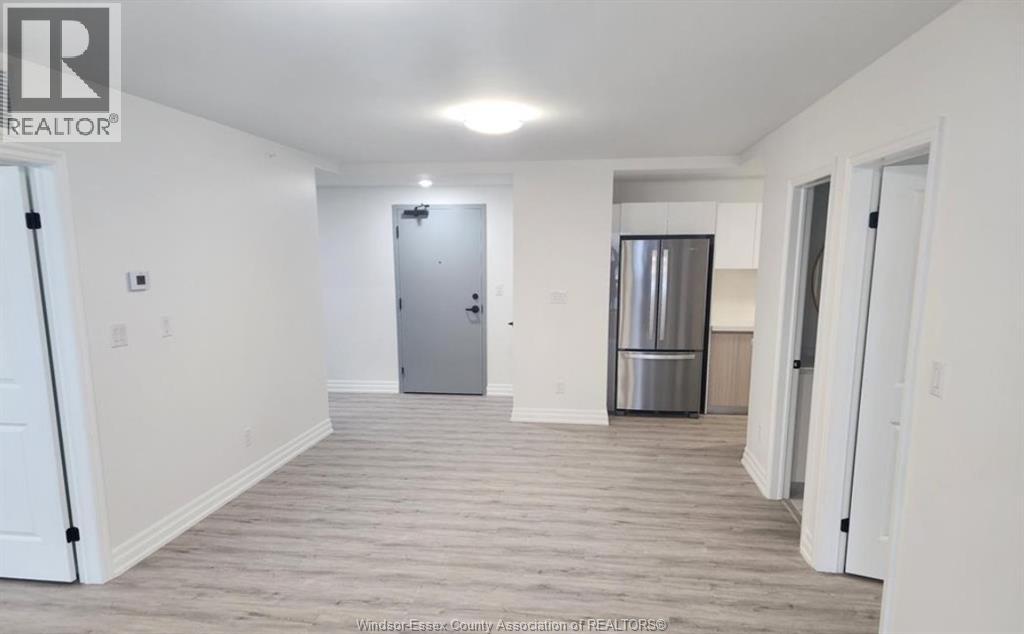 A spacious room with a door and a refrigerator in the background.