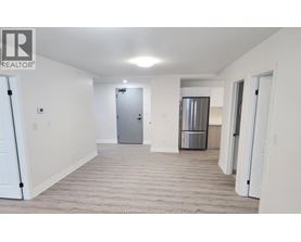 A spacious room with a door and a refrigerator in the background.