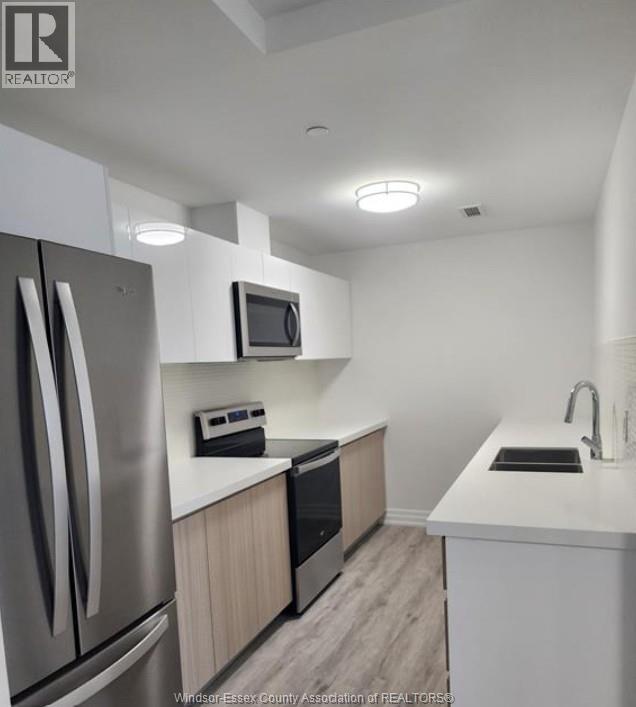 A kitchen with a refrigerator, microwave, oven, sink and countertop.