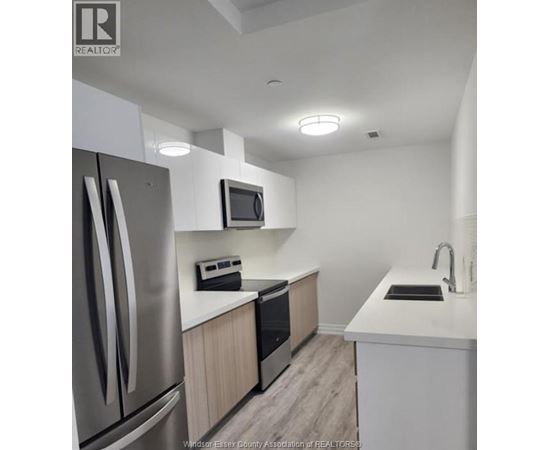 A kitchen with a refrigerator, microwave, oven, sink and countertop.